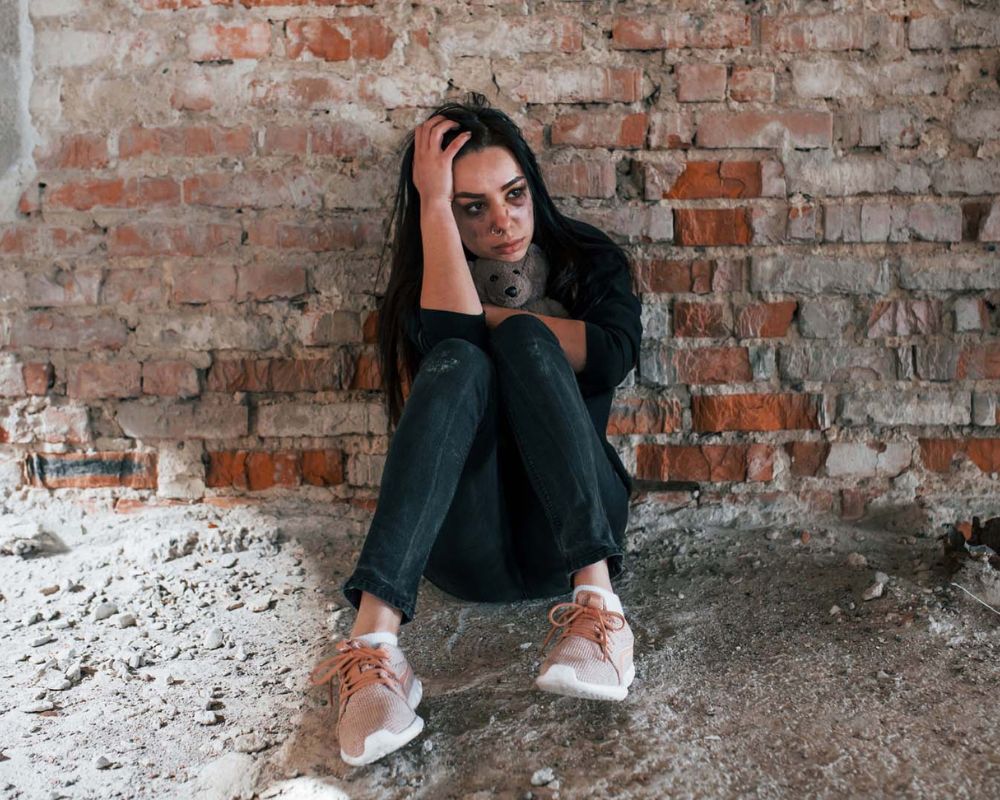 Mujer joven con rostro angustiado abrazando un peluche, simbolizando el impacto de la violencia sexual y la necesidad de asistencia legal experta.