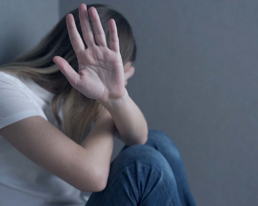 Mujer con gesto de rechazo y miedo, representando la violencia doméstica y de género y la necesidad de asistencia legal especializada.